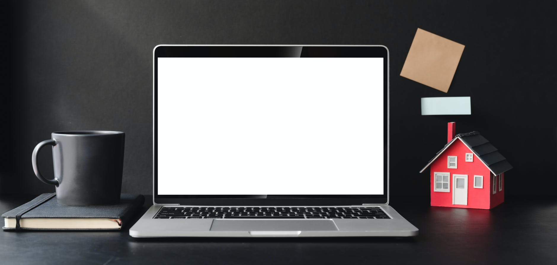 laptop and small toy house on desktop
